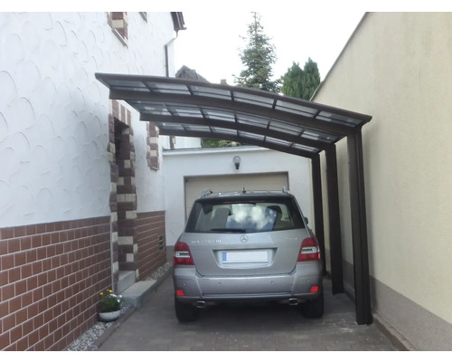 Ein Auto parkt unter einem Carport zwischen zwei Gebäuden.