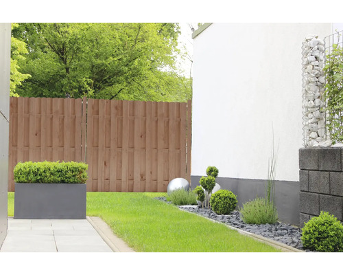 Gartenszene mit Holzzaun, Pflasterweg, Pflanzkästen und Gabionen