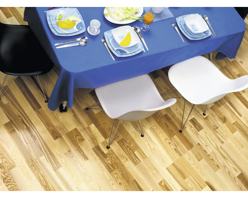 Esstisch mit blauem Tischtuch, Geschirr und Stühlen auf Holzboden