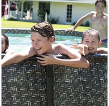 Kinder vergnügen sich in einem Pool mit Rattanverkleidung im Garten.