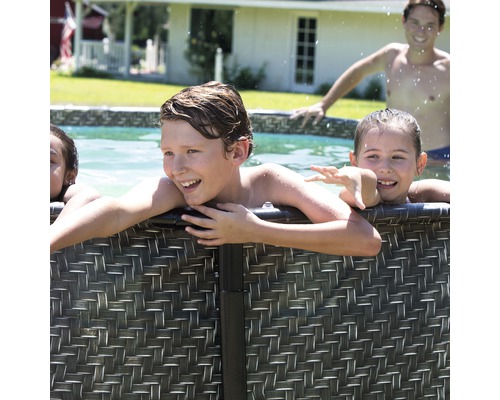 Kinder vergnügen sich in einem Pool mit Rattanverkleidung im Garten.