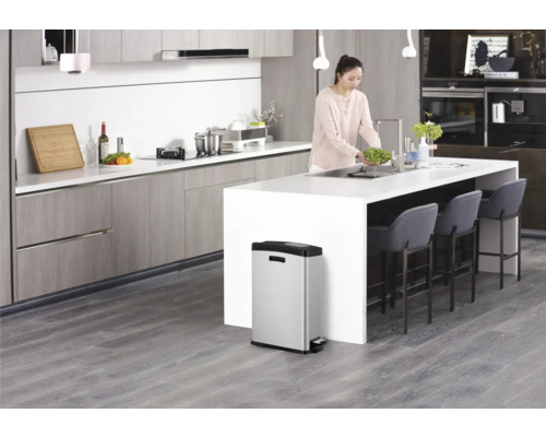 Moderne Küche mit Frau am Waschbecken und Edelstahl-Treteimer