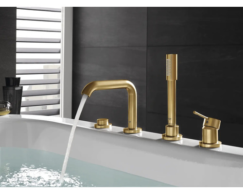 Goldfarbene Badewannenarmatur mit Handbrause auf einer weißen Badewanne