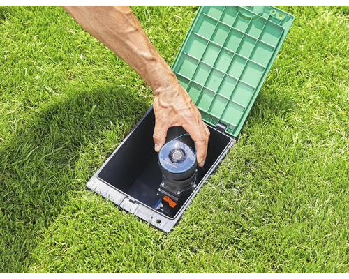 Versenkregner wird in ein schwarzes Gehäuse auf einem Rasen eingesetzt