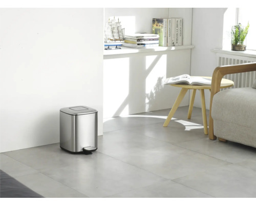 Innenaufnahme eines Zimmers mit einem silberfarbenen Tretmülleimer aus Metall.