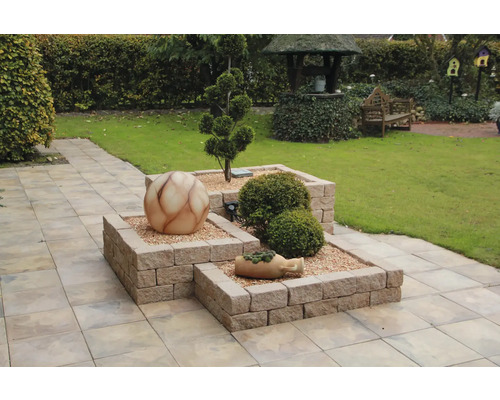 Gartenszene mit erhöhten Beeten aus Mauersteinen, Dekokugel und Bepflanzung