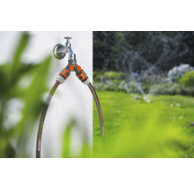 Gartenszene mit Wasserhahn, Verteiler und Gartenschläuchen zur Bewässerung