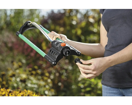 Frau montiert einen Rasensprenger im Garten