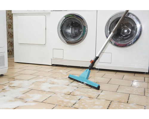 Wischmopp mit Abzieher vor Waschmaschinen auf gefliestem Boden