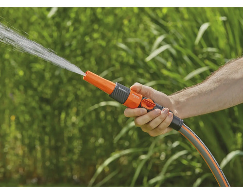 Eine Hand hält eine Gartendusche, aus der Wasser spritzt.