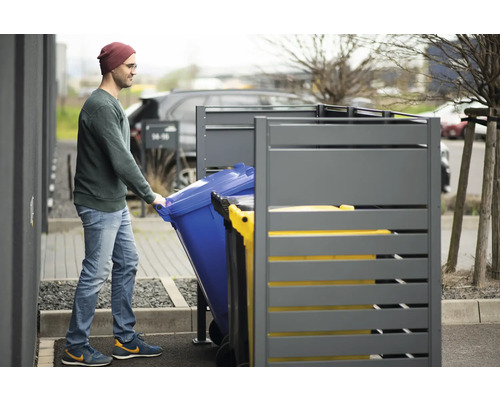 Mann schiebt Mülltonne in Mülltonnenbox