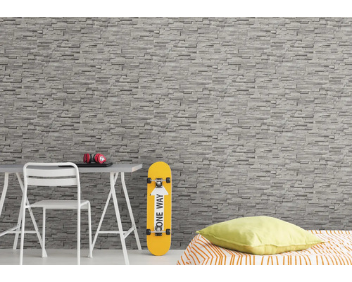 Wohnraum mit Steintapete, Schreibtisch, Stuhl, Skateboard und Bett