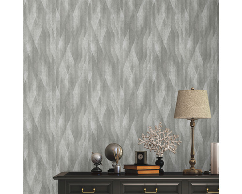 Szene mit grauer Vliestapete mit geometrischem Muster an einer Wand über einer Kommode.