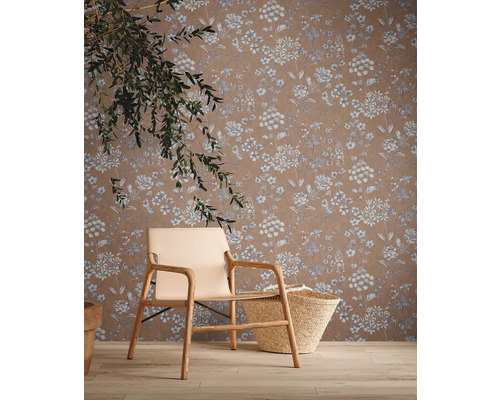 Wohnraum mit floral gemusterter Tapete, Sessel und Korb