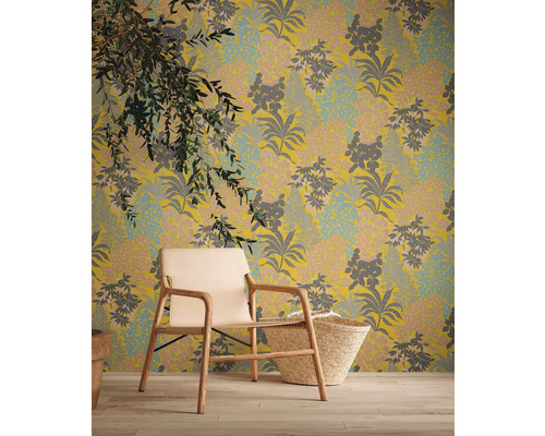 Dekorative Tapete mit floralem Muster, kombiniert mit einem Sessel und einem Korb für eine gemütliche Raumatmosphäre.