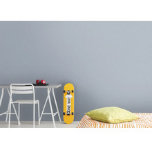 Jugendzimmer mit Schreibtisch, Stuhl, Kopfhörern, Laptop, Skateboard und Kissen.