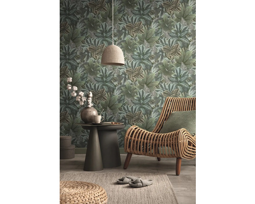 Wohnraum mit Blättertapete, Rattansessel und Beistelltisch