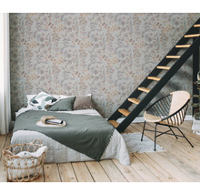 Schlafzimmer mit floral gemusterter Tapete, Bett, Leiter und Korbsessel