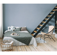 Helles Schlafzimmer mit Bett, Leiter, Stuhl und Wäschekorb auf Holzboden