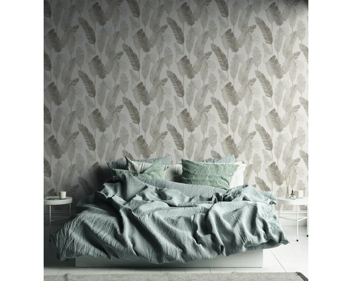 Schlafzimmer mit Bett und gemusterter Tapete mit Blattmotiv