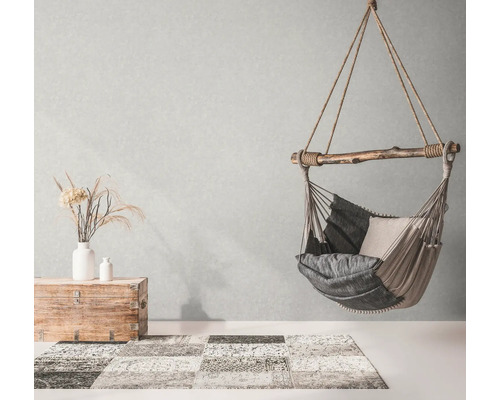 Hängesessel mit Kissen, Truhe und Teppich in einem hellen Raum