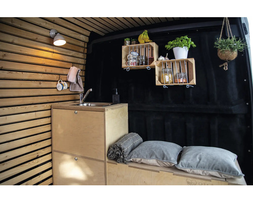 Innenraum eines Vans mit Holzwand, Küchenzeile mit Spüle, Regalen und Sitzgelegenheit