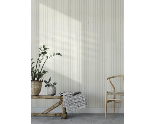 Ein heller Raum mit Holzvertäfelung, einer Holzbank mit Strickdecke und einem Holzstuhl.