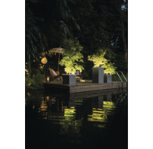 Szene mit beleuchteten Pflanzenkübeln und Gartenmöbeln am Wasser