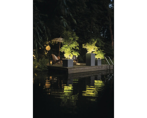 Szene mit beleuchteten Pflanzenkübeln und Gartenmöbeln am Wasser