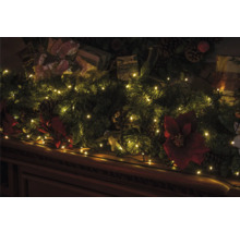 Dekorierter Sims mit Tannengrün, Geschenken, Tannenzapfen, Weihnachtsstern und Lichterkette