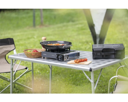 Campingtisch mit Gaskocher, Pfanne, Gemüse und Zubehör im Freien