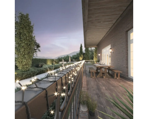 Terrasse mit Lichterkette an einem Geländer mit Garten im Hintergrund.