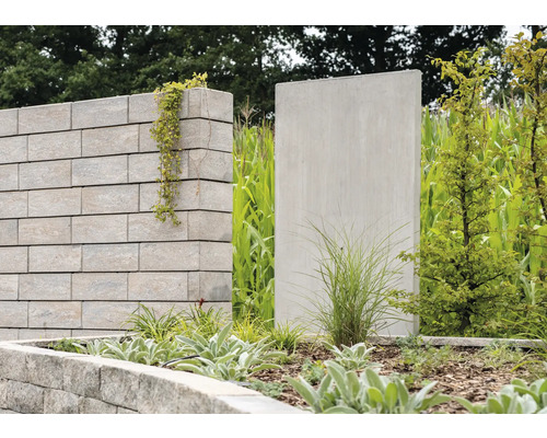 Gartenszene mit Mauer aus Steinblöcken, Beet und Betonwand