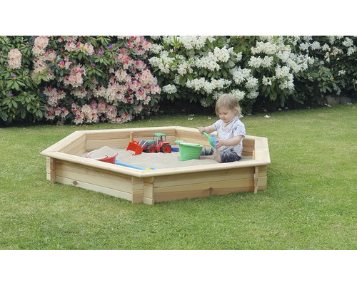 Kind spielt im Sandkasten aus Holz im Garten