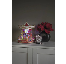 Dekoratives Karussell mit Beleuchtung, neben einem Glas mit Marshmallows und einer Vase mit Blumen auf einem Schrank