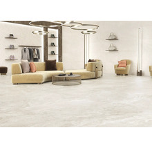 Heller, gefliester Raum mit Sofa, Sessel, Kleiderständer und dekorativen Accessoires.