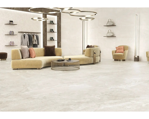 Heller, gefliester Raum mit Sofa, Sessel, Kleiderständer und dekorativen Accessoires.
