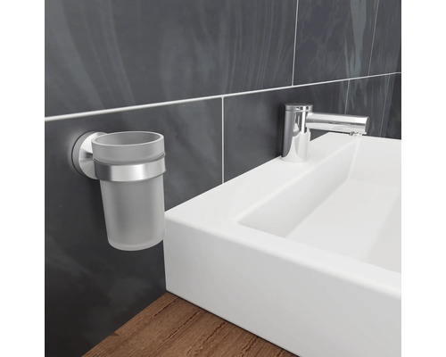 Wandmontierter Zahnputzbecherhalter aus Glas und Metall neben einem Waschbecken