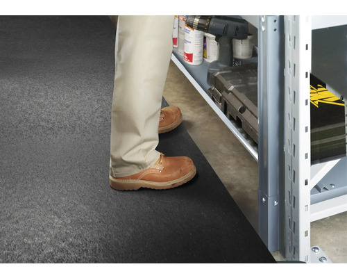 Mann steht auf einer Gummimatte vor einem Lagerregal mit Werkzeugen und Zubehör.