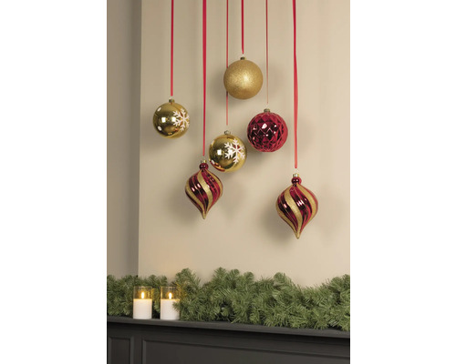 Dekorative Weihnachtskugeln und Girlande über einem Kaminsims