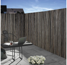 Sichtschutzzaun aus Naturmaterial neben einem Gartentisch mit Laptop im Außenbereich.