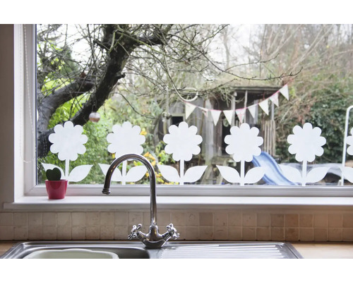 Fensterdekoration mit Blumenmotiven, Spüle und Wasserhahn im Vordergrund