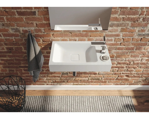 Modernes Badezimmer mit Waschbecken, Armatur und Spiegel an einer Backsteinwand