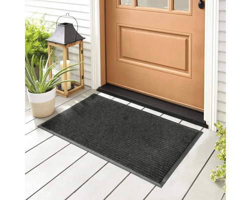 Graue Fußmatte vor einer Haustür mit Dekorationsgegenständen