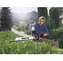 Ein Mann schneidet eine Hecke mit einer Heckenschere im Freien.