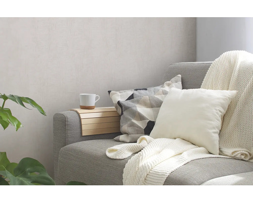 Graues Sofa mit Kissen und Decke in einem hellen Wohnraum.