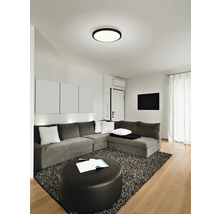 Wohnzimmer mit grauer Couch, Teppich und runder Deckenleuchte