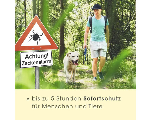 Mann geht mit Hund im Wald an Warnschild Zeckenalarm vorbei