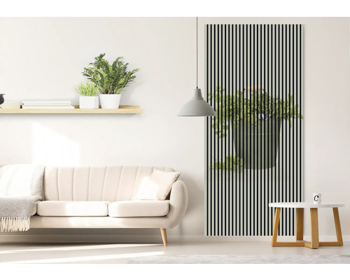 Wohnzimmer mit Sofa, Tisch und Wanddekoration mit Pflanzenmotiv hinter schwarzen Streifen