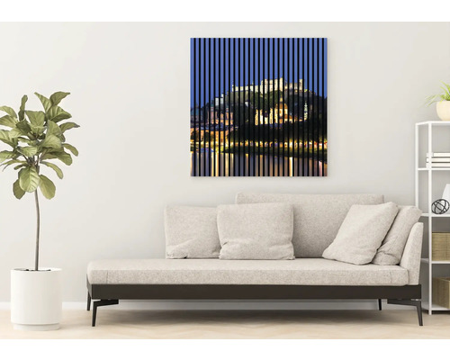 Dekorative Wandkunst mit einem Motiv einer Stadtansicht hinter vertikalen Linien über einem Sofa in einem Wohnzimmer.